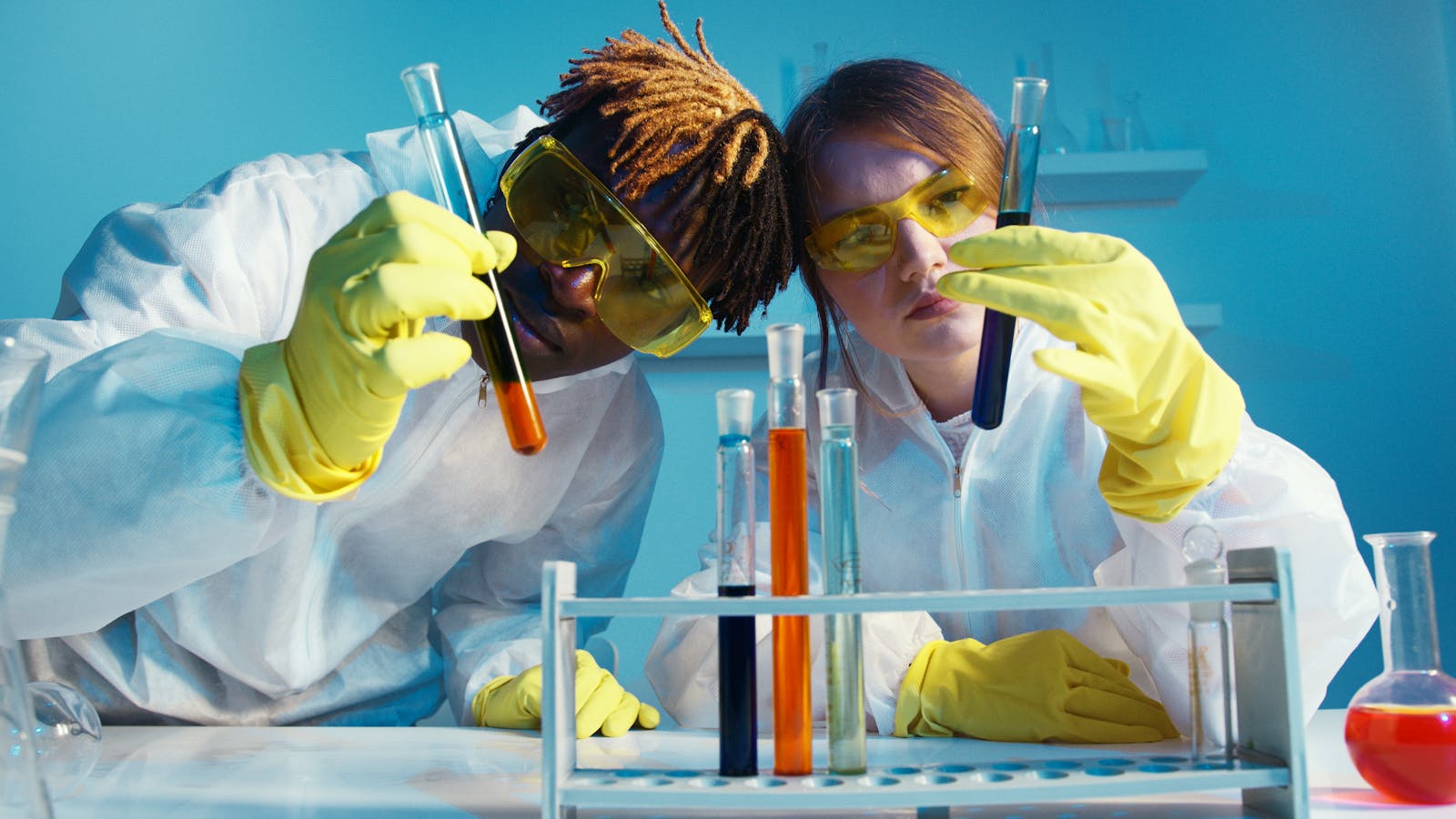 Photo by Artem Podrez Two scientists in protective gear analyzing test tubes in a laboratory setting.